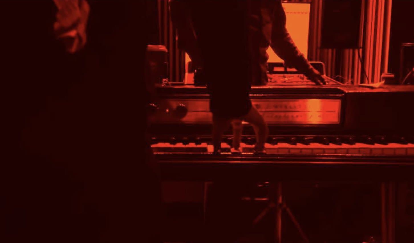 Hands on an electric piano, washed in red light