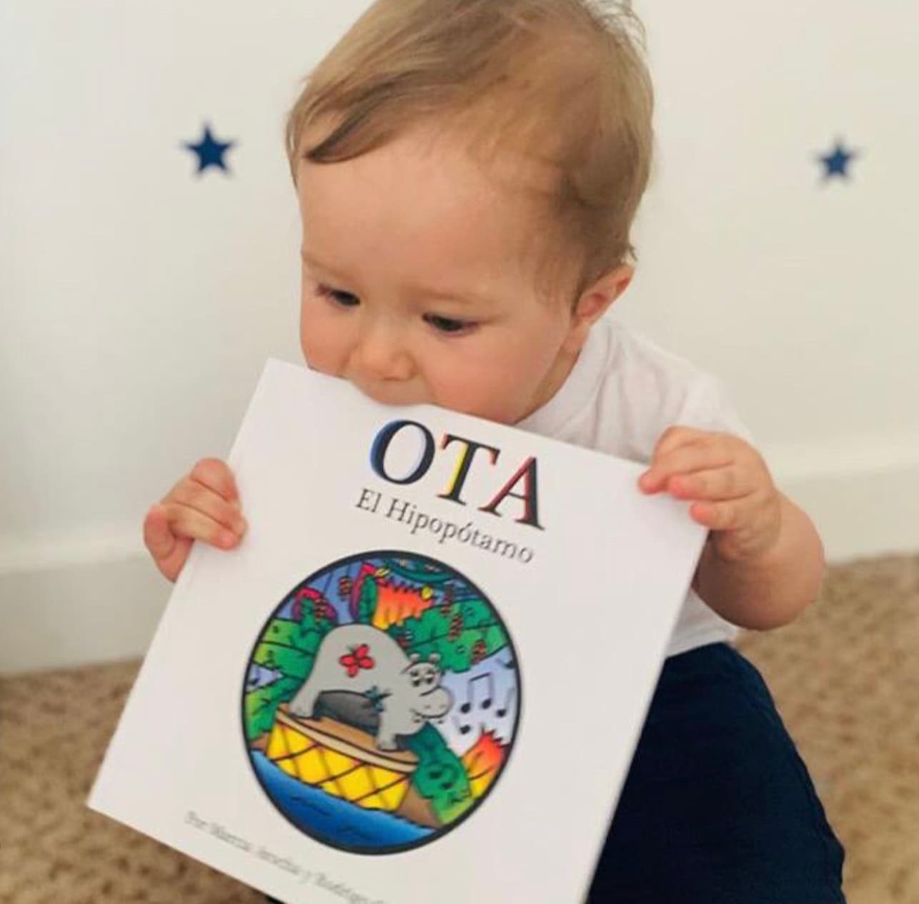 A baby holding the OTA El Hipopótamo book