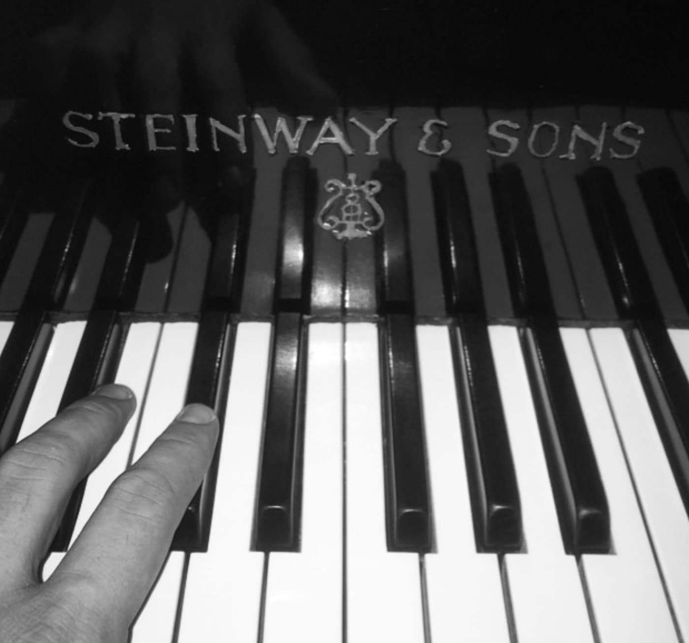 Hands resting on Steinway & Sons piano keys