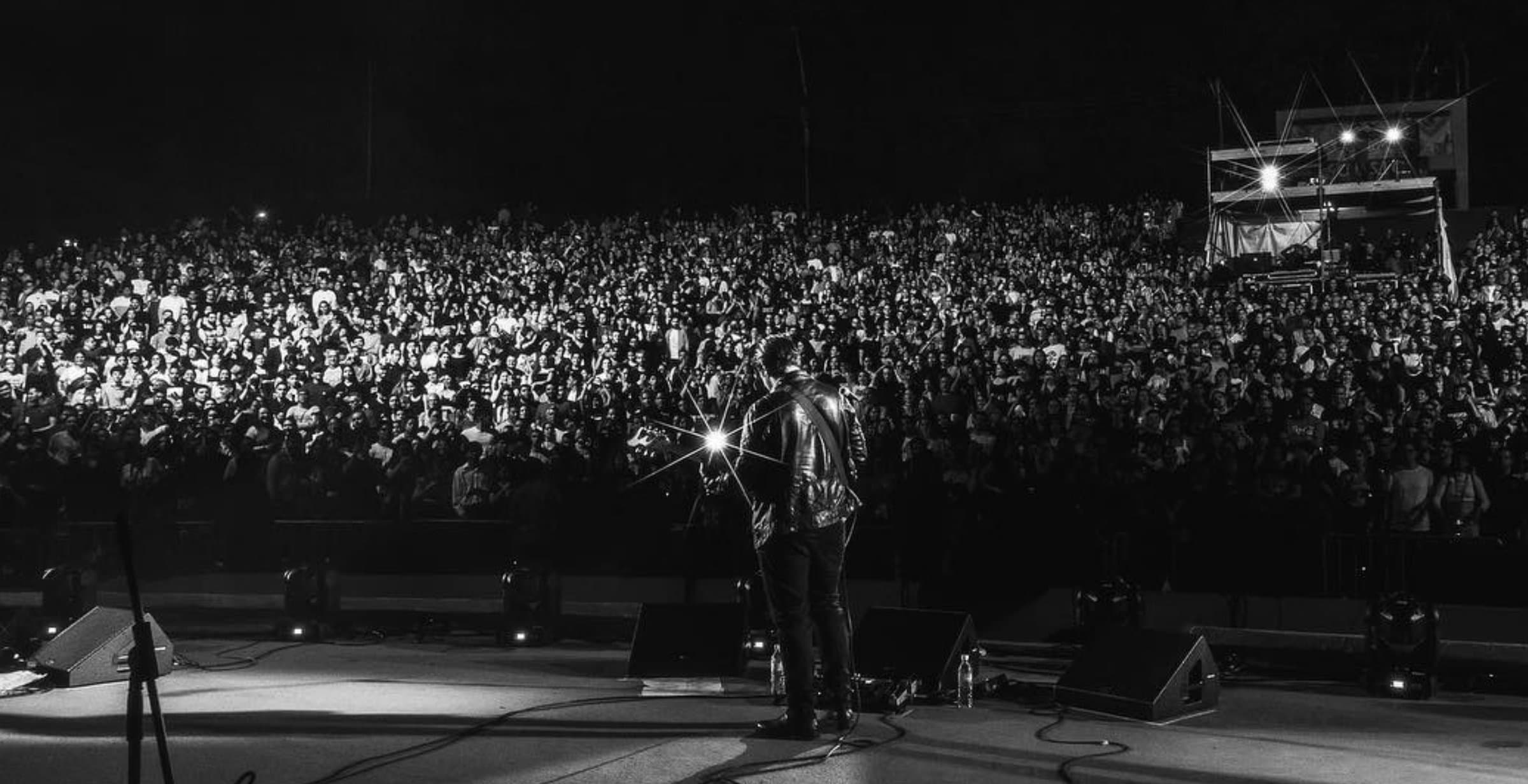 From behind the stage — a packed amphitheater, one spotlight on the singer