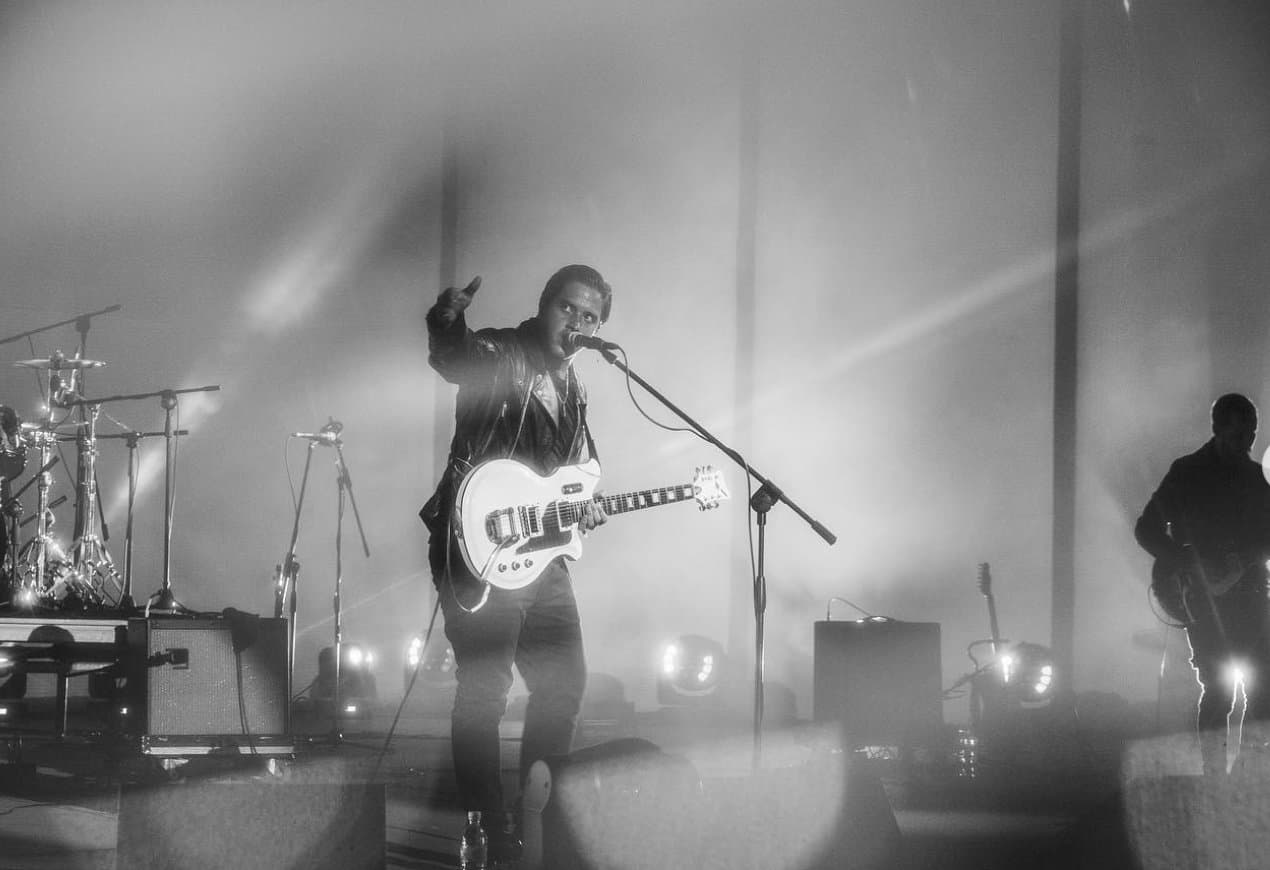 Pointing into the haze, white guitar in hand
